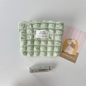 Detail of light green bubble gauze makeup bag with textured fabric and white label