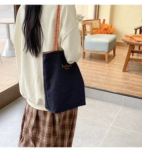 Dettaglio della borsa tote in denim con tracolla di perline arancioni e ricamo retrò