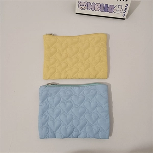 Detail of heart-quilted storage pouches in yellow and blue with metal zippers
