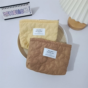 Detail of yellow and brown heart-quilted cosmetic bags in a cozy wooden tray