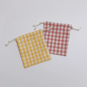 Detail of yellow and red gingham drawstring storage bags in soft cotton fabric