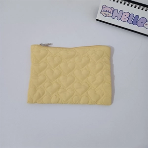 Macro shot of yellow quilted heart pouch featuring soft fabric and silver metal zipper