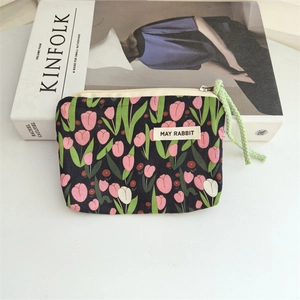 Detail of floral fabric pouch with tulip patterns, green cord zipper, and woven label