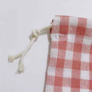 Detail of red and white checkered storage bag showing cotton texture and drawstring