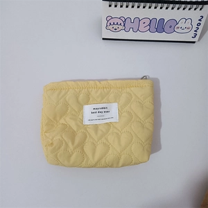 Detailed view of yellow heart quilted makeup bag with zipper closure and white label
