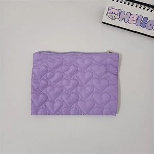 Macro view of purple quilted heart pattern on a small pouch with a smooth zipper detail