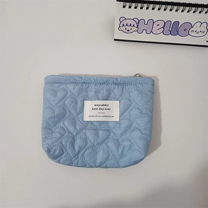 Detailed view of light blue quilted heart cosmetic bag with zipper and logo label