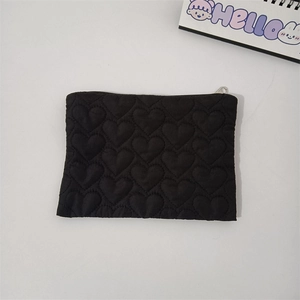Detailed view of black quilted heart pattern on the portable mini cosmetic bag