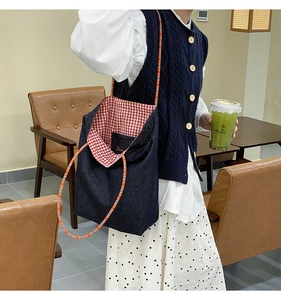 Dettaglio della borsa in denim con fodera a quadri rossi e tracolla a righe colorate