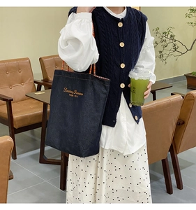 Dettaglio della borsa tote in denim con ricamo giallo e fodera a quadretti rossi e bianchi