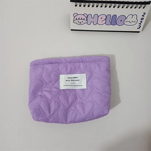 Detail of purple quilted heart makeup bag with textured nylon fabric and woven label