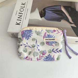 Detail of floral cotton coin purse with zipper closure and woven purple rope handle