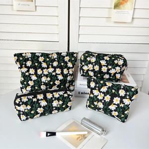 Detailed set of four black makeup bags with white daisy embroidery and silver zippers