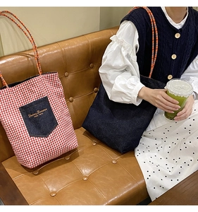 Dettaglio della borsa tote in tela a quadretti rossi e borsa a spalla denim