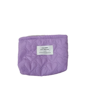 Purple quilted heart pattern cosmetic bag with a small woven brand label on white background