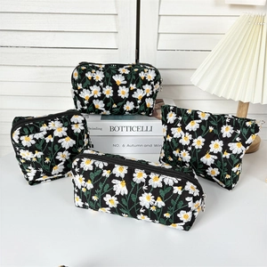 Detail of four-piece black canvas makeup bags with white daisy embroidery and silver zippers