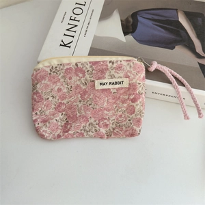 Close-up of small floral cotton coin purse with pink rose pattern and woven zipper rope