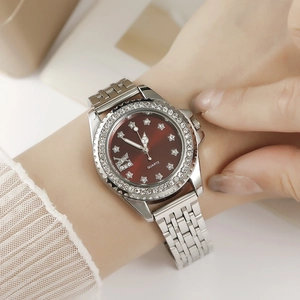 Détail de montre en acier argenté avec lunette diamantée, cadran rouge et index étoile