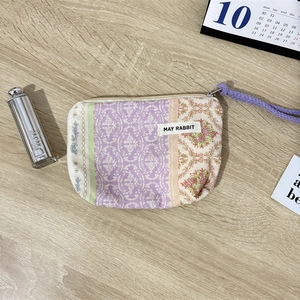 Detailed top view of a floral cotton coin purse with purple wristlet strap on a wooden desk