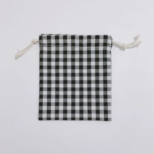 Close-up of small black and white plaid cotton drawstring storage bag with white cords