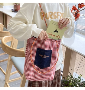 Dettaglio della borsa tote in tela a quadretti rossi con tasca in denim e manico in corda