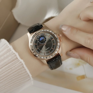 Détail d'une montre à quartz or rose avec lunette en strass et bracelet en cuir noir