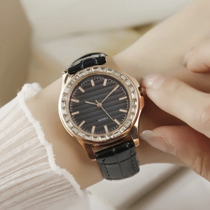 Moderne Damenquarzuhr mit Kristalllünette und schwarzem Lederarmband am Handgelenk