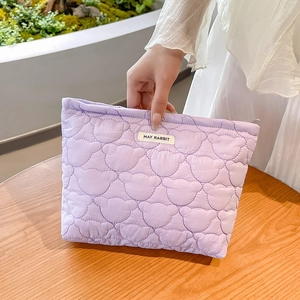 Detailed close-up of light purple quilted cosmetic bag with cute bear pattern and logo