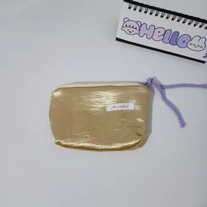 Close-up of golden textured pouch with purple woven zipper pull and Mayrabbit label