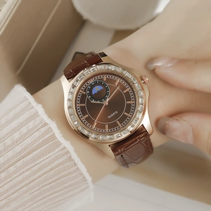 Détail de montre en or rose avec lunette diamantée et bracelet en cuir crocodile brun