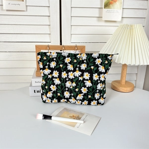 Detail of embroidered white daisy patterns on a black canvas makeup organizer bag