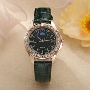 Détail d'une montre à quartz or rose avec phase de lune et bracelet en cuir vert