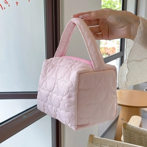 Quilted heart pattern makeup bag with handle in soft pink showing detailed fabric texture