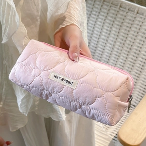 Detail of pink quilted pencil case featuring heart patterns and May Rabbit woven label