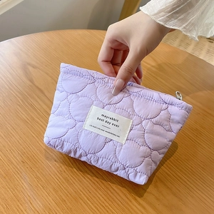 Close-up of lavender quilted makeup bag with signature label and zipper detail