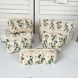 Detail of five-piece set daisy embroidered travel pouches with metal zippers