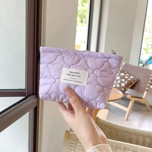 Detailed view of light purple quilted makeup bag with heart patterns and zipper closure