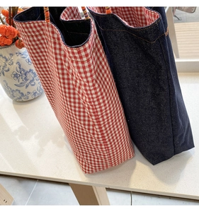 Dettaglio di borse tote reversibili in denim e quadri rossi con manici in corda intrecciata