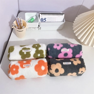 Macro shot of four floral lamb wool pencil cases with woven brand labels and zipper detail