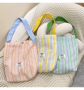 Detailansicht bunter gestreifter Canvas-Tragetaschen mit farbigen Macaron-Trägern