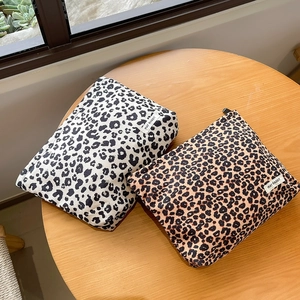 Detail view of leopard print corduroy makeup bags with zippers on a wooden table