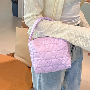 Detail of light purple quilted cosmetic bag with heart pattern and sturdy handle strap