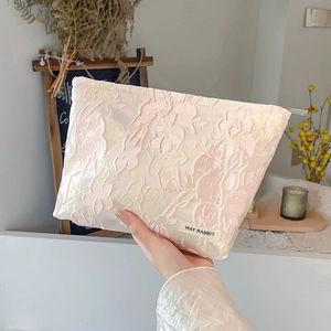 Detailed texture of pink floral embossed jacquard fabric on travel makeup bag