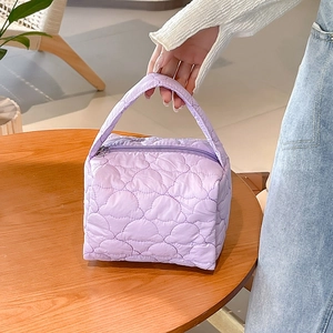 Close-up of light purple quilted cosmetic bag with heart patterns on a wooden table