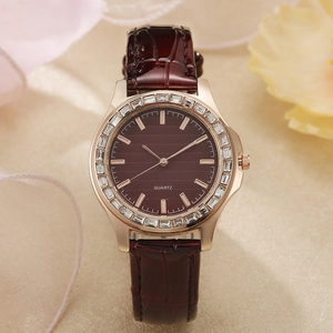Detail der roségoldenen Uhr mit Baguette-Kristalllünette und burgunderrotem Lederband