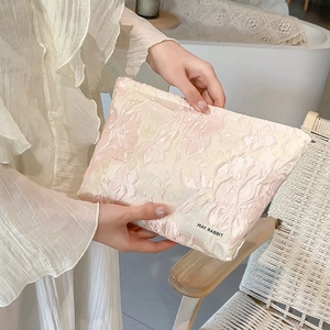 Detail shot of pink jacquard makeup bag with floral relief and May Rabbit label