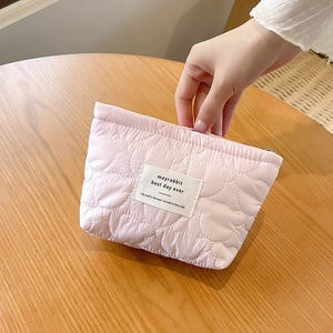 Detail of pink quilted cosmetic bag with heart pattern texture and woven label design