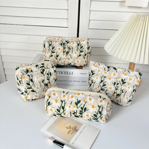 Detail of four-piece set daisy embroidery makeup bags in cream canvas with zippers