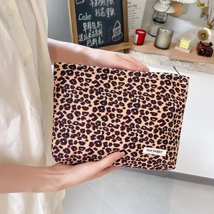 Fashionable corduroy leopard print makeup bag with zipper and logo label held by a person