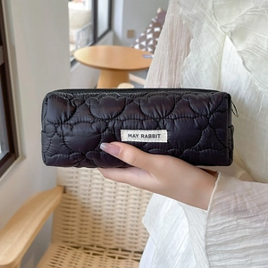 Quilted black pouch with MAY RABBIT label and metal zipper ring in a lifestyle setting